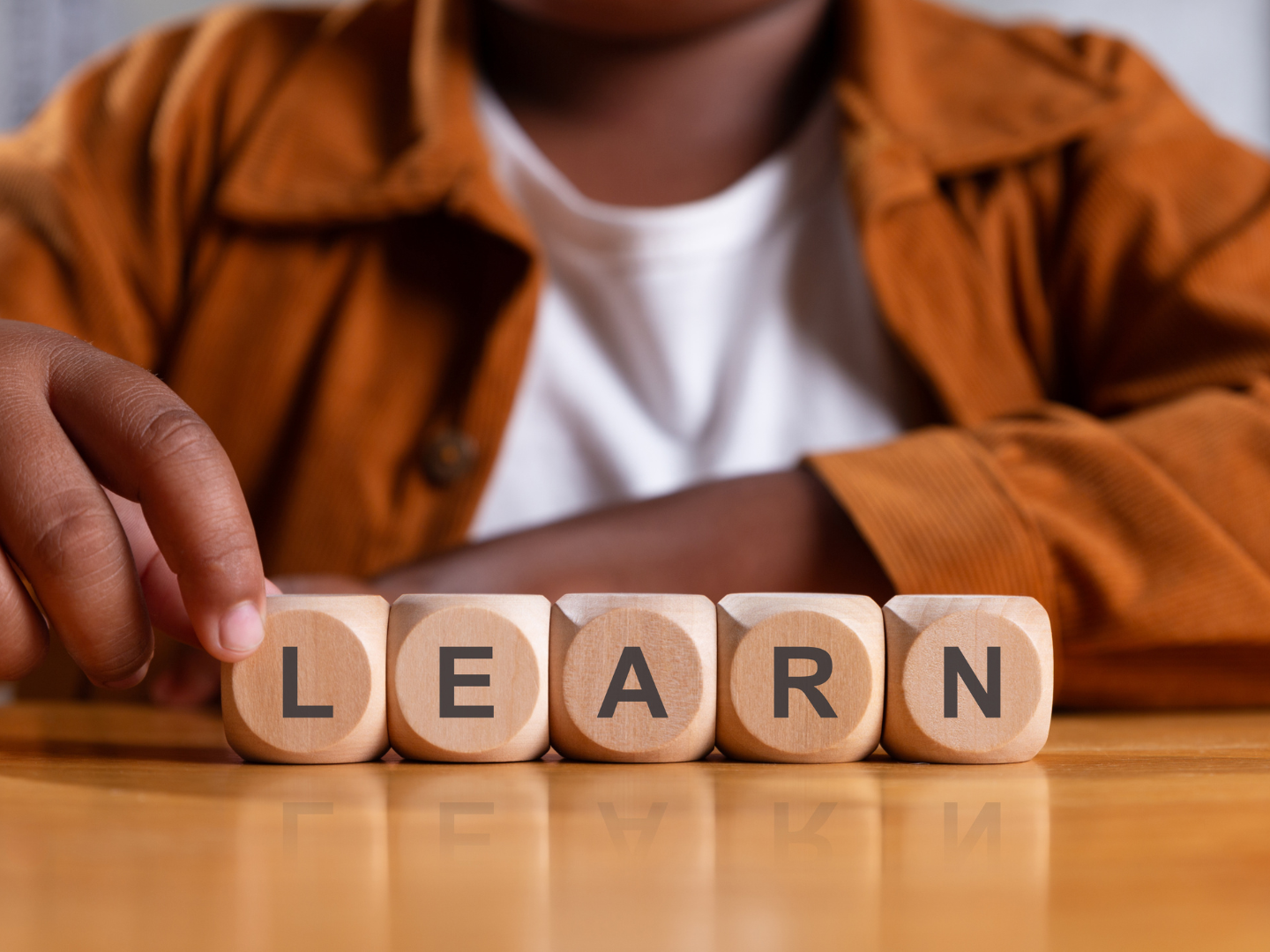 Small wooden blocks spelling LEARN on a warm neutral surface, representing Eloi & Stella's practical courses on self-awareness and holding space